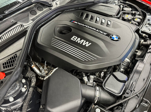 The M Performance Engine Cover With BMW Badge And Branding Of A B58 Turbocharged Engine In A BMW M140i Hatchback. BMW sport engine or motor under vehicle hood.