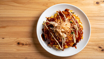 Japanese okonomiyaki served on a white plate placed a wooden table