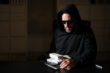 Thief stolen money after a robbery. A masked thief steals money from an office in dark night...