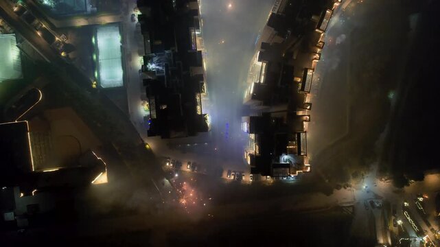 aerial drone shot moving forward looking down at building decorated with lights for Indian festival of diwali with fireworks being burst and smoke trapped showing increase in air pollution