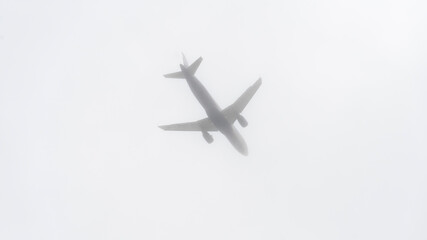 A plane is flying through a cloudy sky. The sky is overcast and the plane is low to the ground
