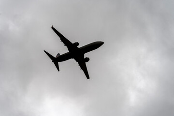 A large airplane is flying through a cloudy sky. Concept of freedom and adventure, as the airplane soars through the air, leaving a trail of white clouds in its wake