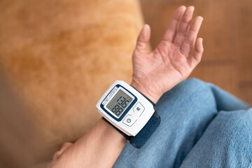 Intelligent blood pressure monitor displays reading while user relaxes on the couch with a pet in the background