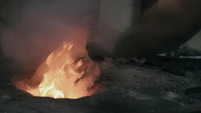 Elderly man in his workshop plates the copper bowl with tin. Tinsmith covering the copper object with tin over fire
