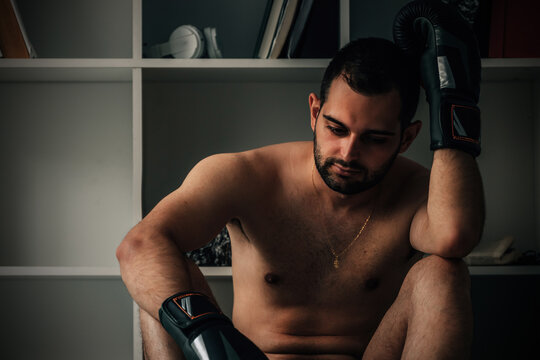 pensive boxer athlete resting with boxing gloves