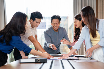 group of colleagues in formal clothing discussing business ideas while gathering at table in modern office and working together