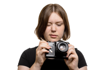 Young woman looking closely at her camera adjusting settings, isolated on transparent background.
