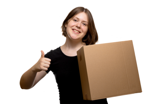 Positive young woman holding a cardboard box and showing thumbs up gesture on transparent background.