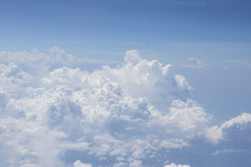 An aerial view of a vast, thick layer of fluffy white cumulus clouds stretching across a bright blue sky, creating a beautiful and serene natural cloudscape from above.