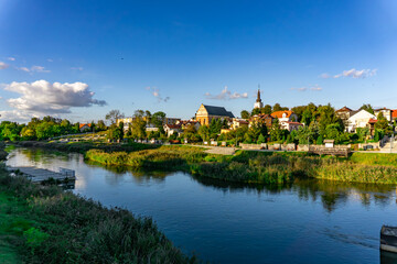 Panoramic view of Uniejów city in the Łódź Voivodeship showing the collegiate church, historic buildings and riverside promenade on a sunny afternoon