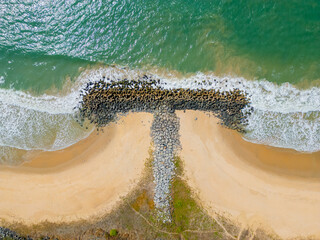 Aerial view of a rocky coastline near Maravanthe Beach, Karnataka, with waves crashing against rugged rocks along the Arabian Sea, creating a dramatic and scenic natural landscape.