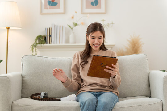 Young Asian woman enjoy while using digital tablet in the modern living room at home