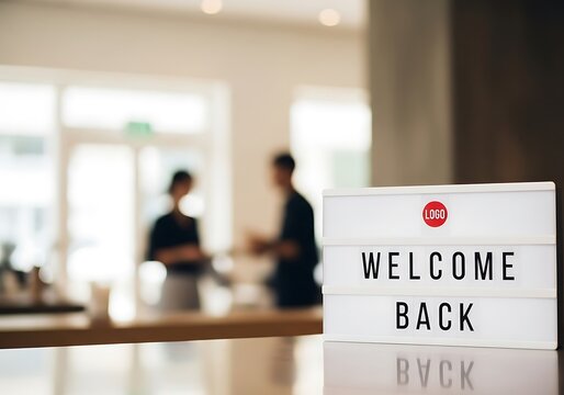 Welcome back sign on table with people in background in the office