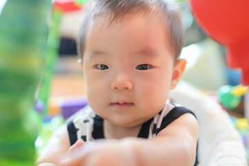 Fototapeta premium A baby is sitting in a high chair and looking at the camera. The baby is wearing a black and white outfit