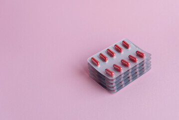 red tablets in blister packs are stacked on a pink background with space for text, allergy medications, antibiotics, and painkillers