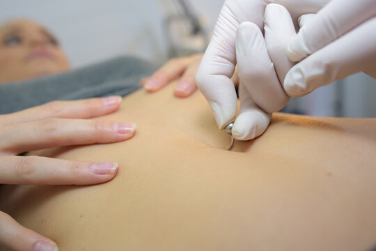 womans hands putting on her heart shaped navel piercing