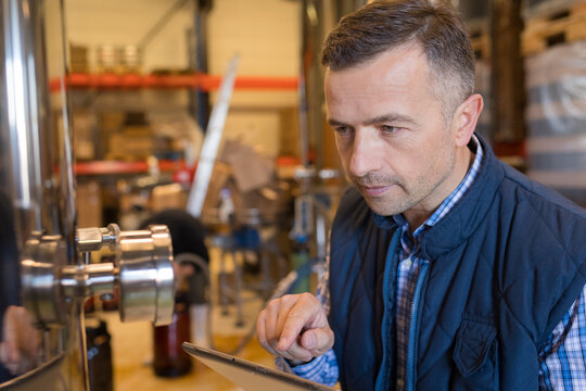 concentrated man making notes in brewery