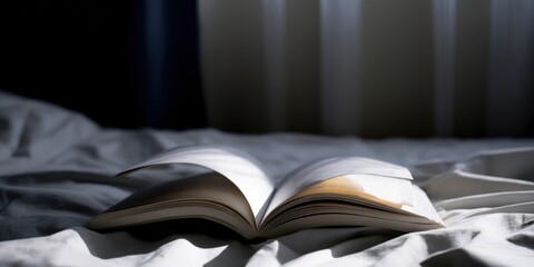 Open book resting on bed with morning sunlight
