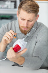 young handsome man repairing egg whisk