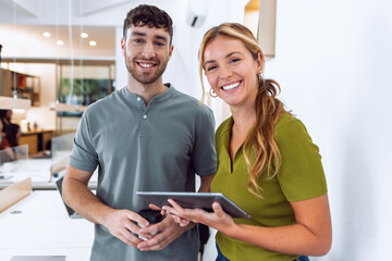 Happy business people working with digital tablet while discussing together in a coworking place