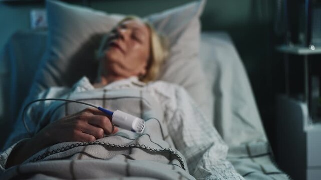 Senior ICU patient with pulse oximeter on finger lying in bed, healthcare scene
