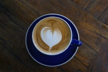 latte art heart in coffee cup on wooden table for cafe and beverage photography
