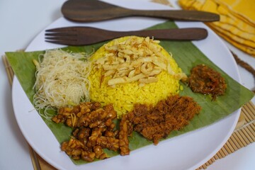 traditional indonesian yellow rice nasi kuning with side dishes for cultural food photography

