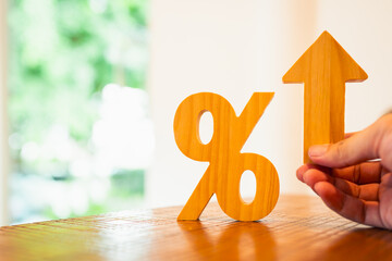 Wooden percentage symbol and upward arrow on table. Ideal for illustrating rising interest rates,...