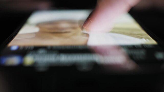Closeup of a hand inserting a black electric plug into a white double socket extension cord. The power strip is on a wooden surface, connecting an appliance and showing home energy consumption.