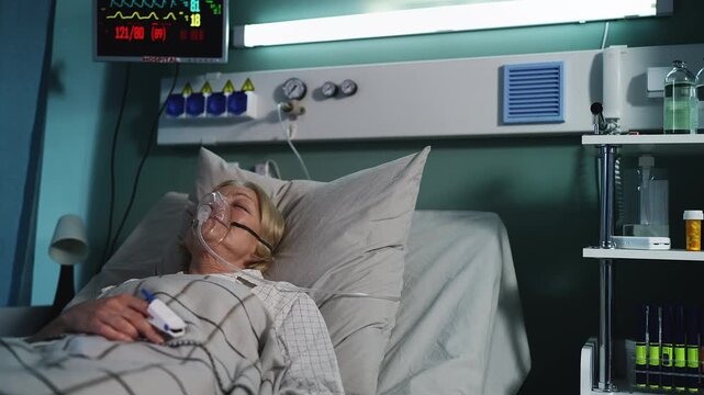 Weak senior woman wearing oxygen mask in ICU room, connected to life support - Powered by Adobe