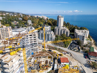Aerial view of a construction site with tower cranes building modern apartments near the sea coast on a sunny day. Urban development concept © sandsun