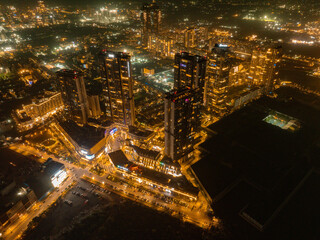 Aerial view of towers illuminated against the dark sky, creating a striking contrast of light and shadow along Golf Course Extension Road, Gurugram, Haryana, India.