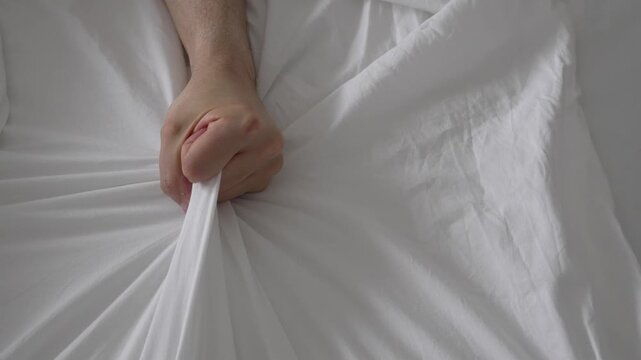 Safe Sex Concept with Hand Grabbing Bed Sheet in Climax Moment