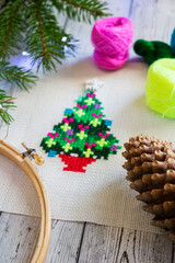 Handmade cross-stitch embroidery of a bright Christmas tree. Cozy holiday needlework and festive winter craft concept.