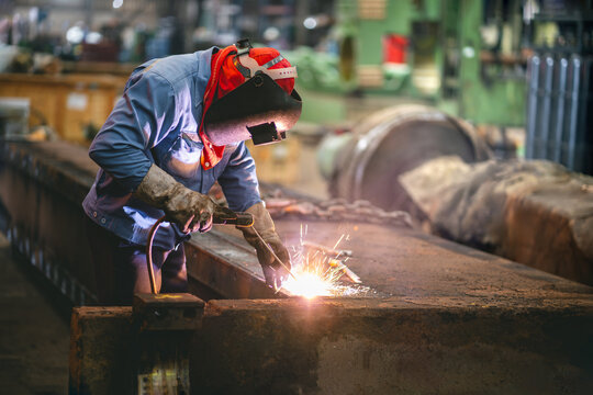 Industrial welder welding repait heavy construction in factory, Welding process by Shielded Metal Arc Welding (SMAW) or Stick Welding.