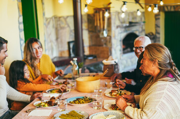 Happy latin family cheering and eating dinner together at home - Winter holidays and Christmas time concept - Main focus on grandmother head