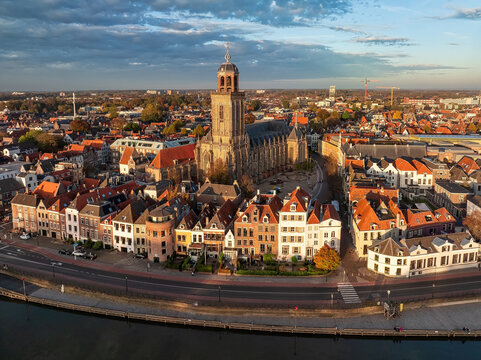 Aerial view of the Lebuinus Church rising majestically above the old town's terracotta rooftops, with the Ijssel River curving along its edge, Deventer, Overijssel, Netherlands.