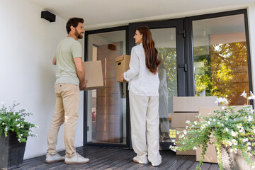 Fototapeta premium Happy couple looking excited while carrying cardboard boxes into the new house