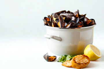Steamed mussels in a pot with lemon and bread