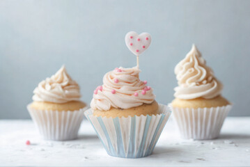 Three frosted cupcakes with sprinkles on a white surface