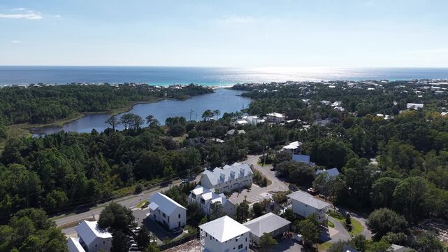 Amazing drone fly at coastal community surrounded by lush green forest near at calm Draper Lake flowing to gulf bay, 30A, Florida, USA