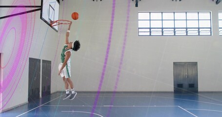 Leaping player wearing green jersey performing dunk at gym court, with basketball hoop, copy space © vectorfusionart