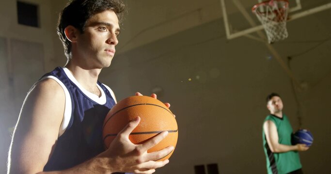 Holding orange basketball, athlete wearing blue jersey warming up on court in gymnasium near hoop - Powered by Adobe