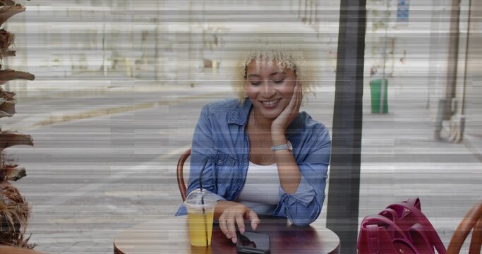 Tapping smartphone woman sitting at wooden sidewalk cafe table, with plastic straw cup red tote bag - Powered by Adobe