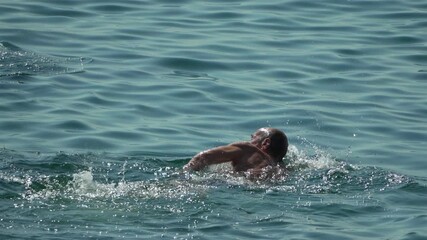 Swimmer, Ocean, Freestyle. A man swims a leisurely crawl stroke in the calm, blue sea.