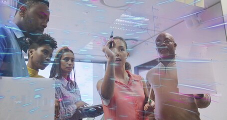 Pointing woman wearing coral blouse marking diagrams on glass board in office, with markers, tablet