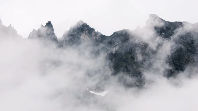 Clouds slowly drift around the majestic Troll Wall ridge in Norway on a misty day
