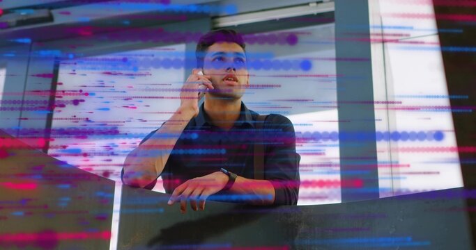 Talking male engineer holding smartphone on office mezzanine railing, with digital code overlay - Powered by Adobe