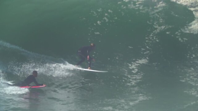 Close up of surfer and bodyboarder on one wave