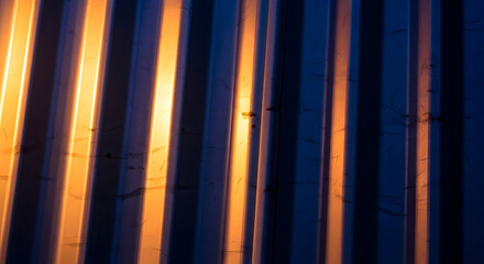 Obraz premium Textured Metal Surface with Vertical Lines and Gradient Light Creating Contrasting Shadows and Warm Tones